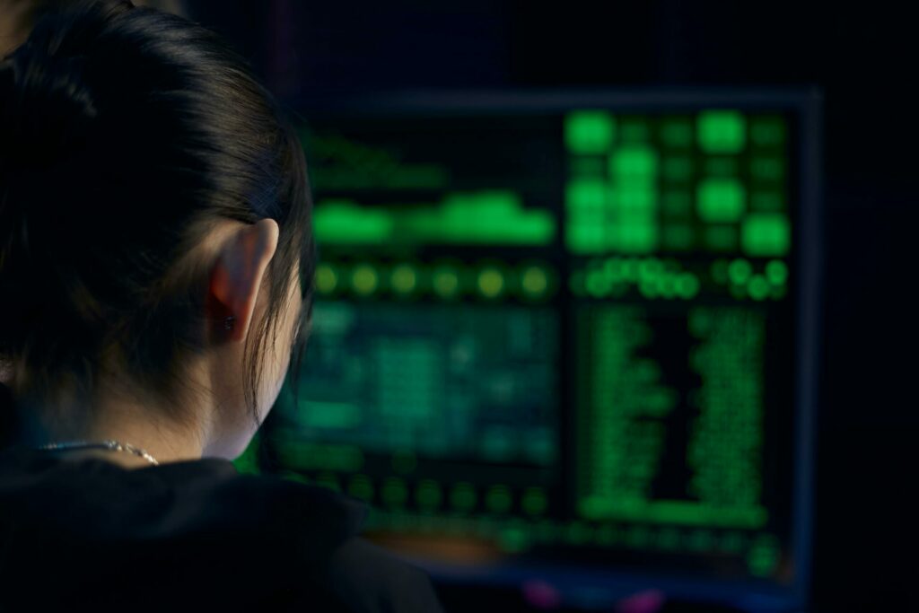 A woman focuses on data displayed on a computer screen in a dark room.